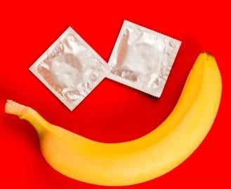 Banana and 2 silver condom packets on a red background, forming a smiling face